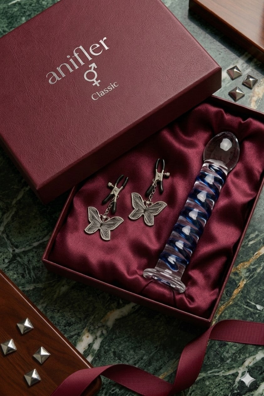 Geöffnete, weinrote Geschenkbox der Marke anifler mit silberner Prägung „Classic“ und den Geschlechtssymbolen für Mann und Frau. Der Karton ist mit weinrotem Seidenstoff ausgelegt und enthält ein spiralförmiges Lovetoy aus blau-transparentem Glas sowie zwei silberne Schmetterlings-Nippelklemmen. (Symbolbild – KI-generierte Beispielillustration).